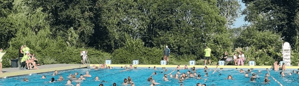 Zwem-Vierdaagse Lansingerland buitenzwembad De Windas met vele deelnemers zwemmend in openluchtbad omgeven door groene bomen